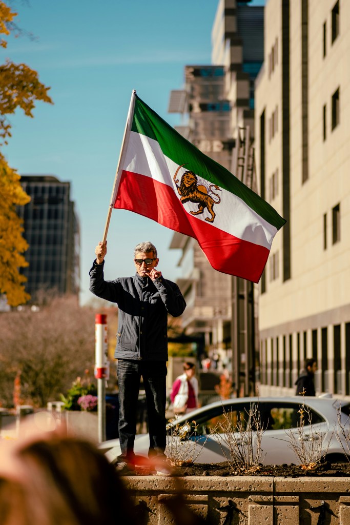 man waving iran lion and sun flag in the street